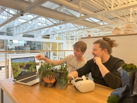 Student presents a Minecraft-based virtual model to Professor Ryan Scavnicky, alongside a physical terrain model on a table. Considering a Game Design Degree? Here’s Why You Should Look at Virtual Architecture